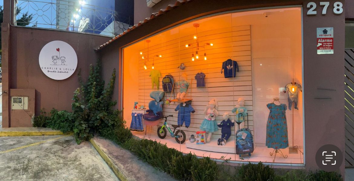 Interior da loja Charlie & Lolla — araras de roupas infantis e prateleiras de brinquedos